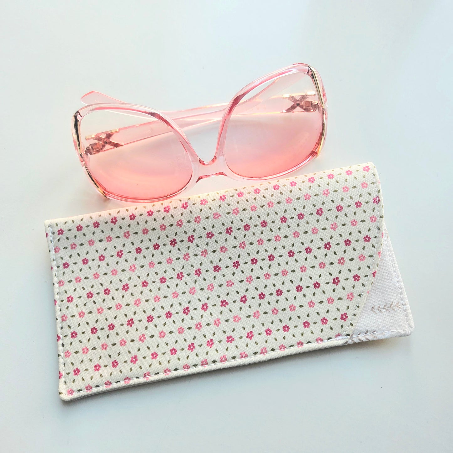 Pink sunglasses on a floral fabric case