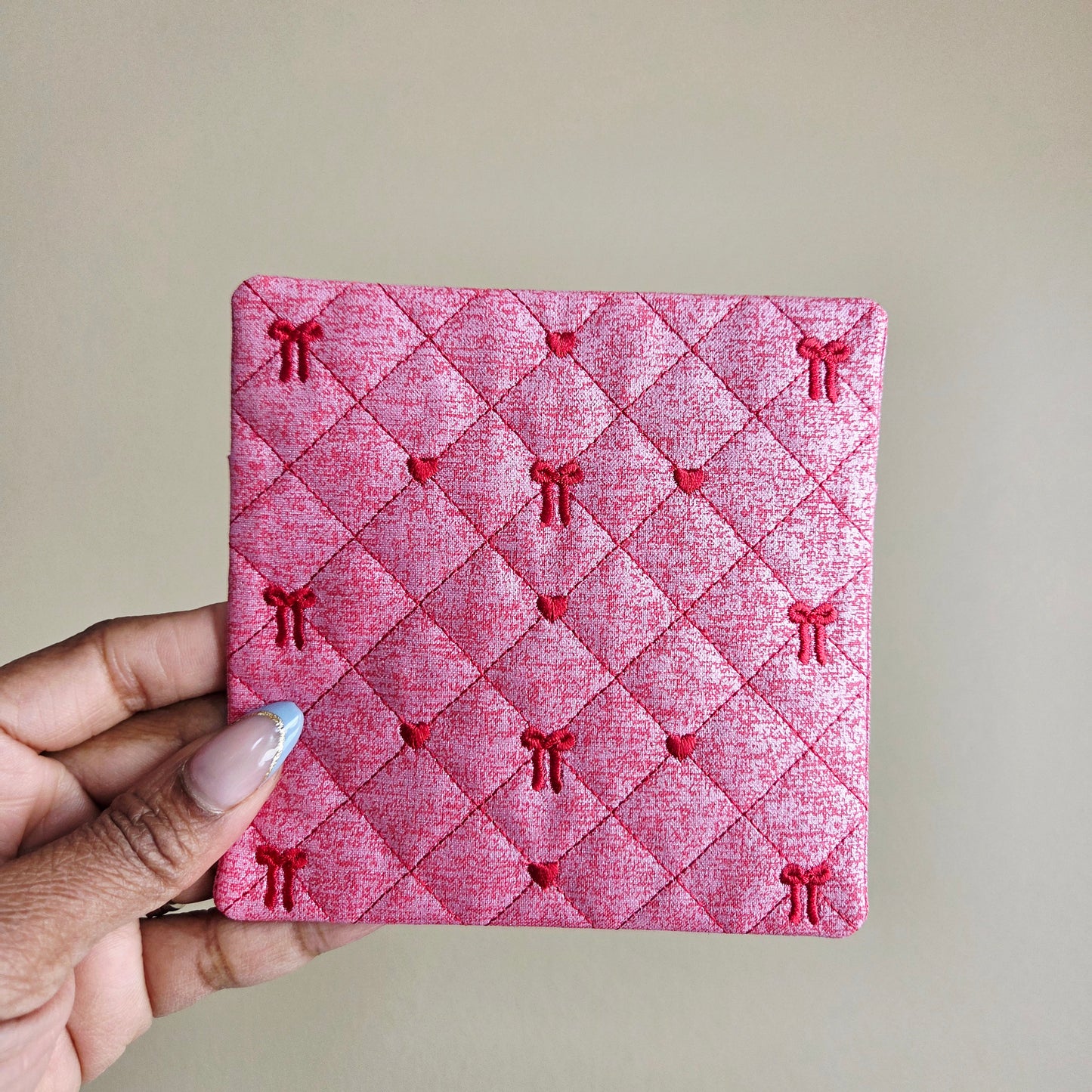 Red quilted Valentine fabric coaster with embroidered bows, padded handmade mug rug