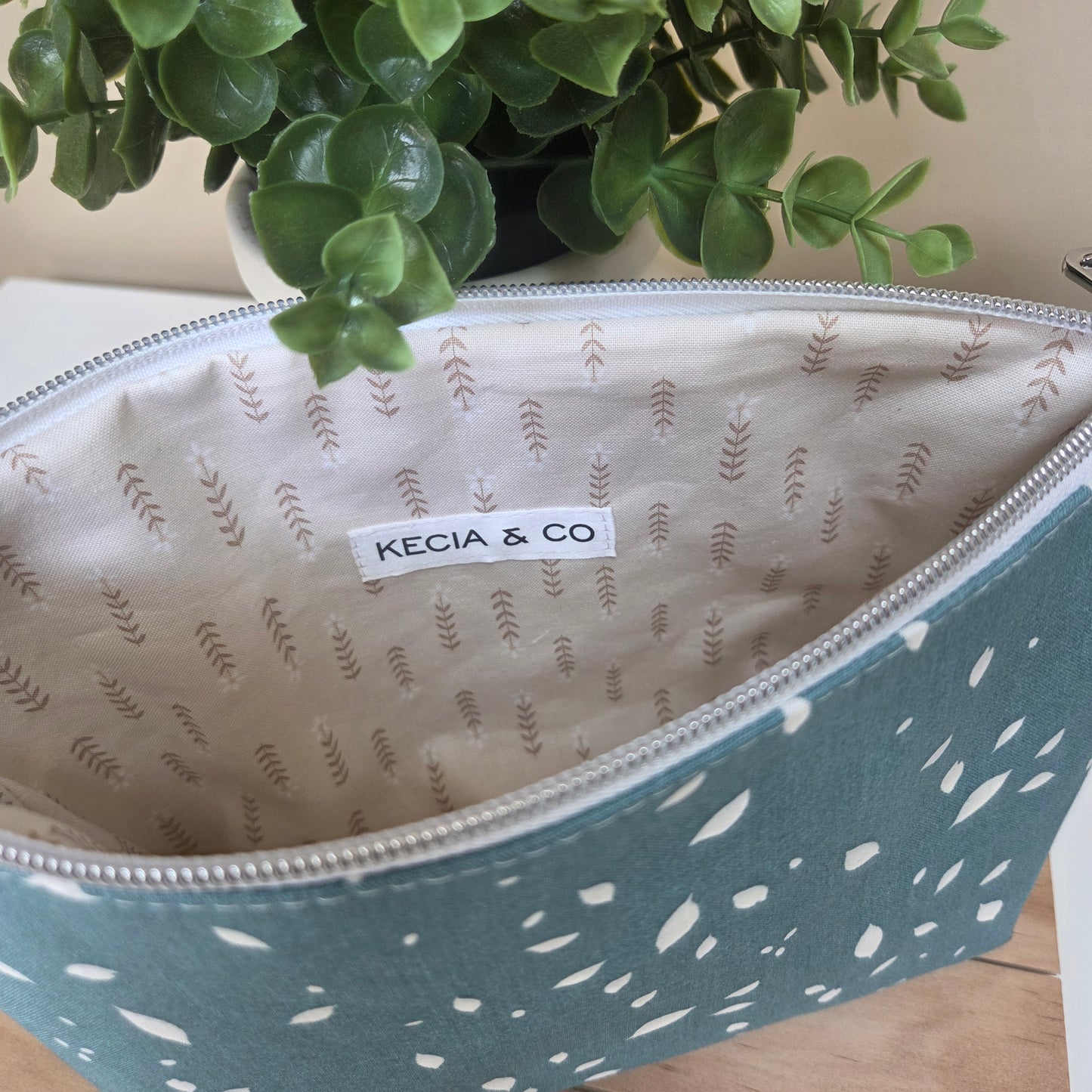 Teal handmade pouch with white scattered spots, featuring a clean ivory interior