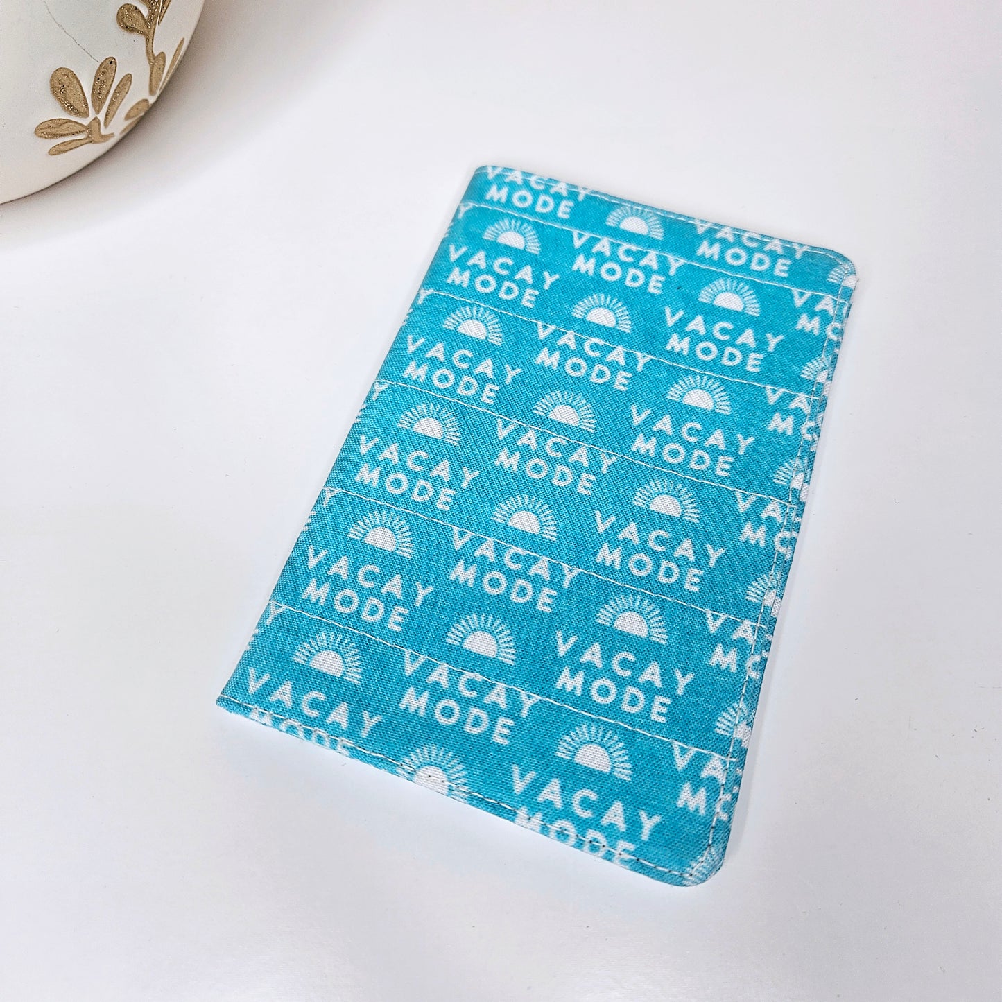 A passport cover with a 'VACAY-MODE' text and geometric patterns in blue