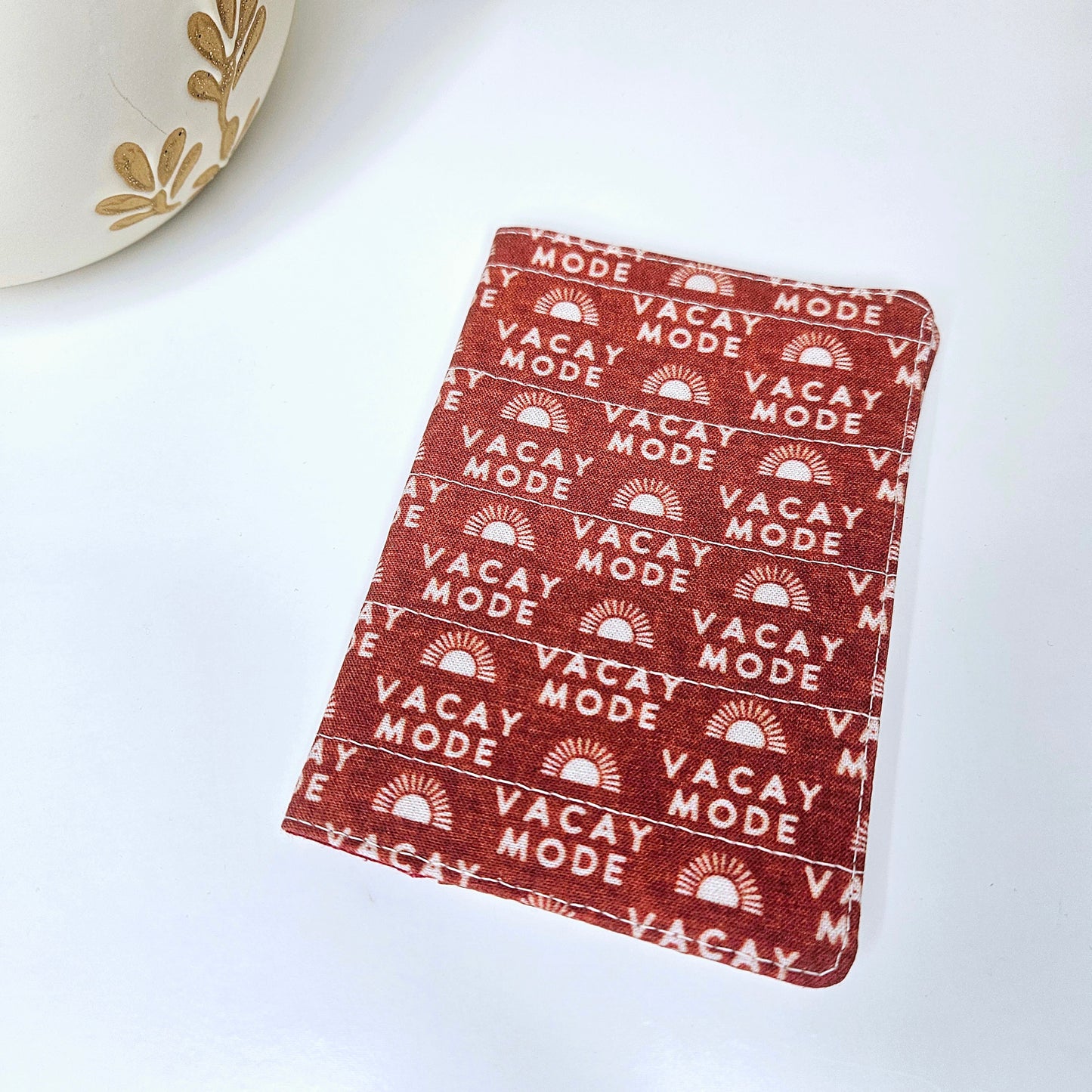 A passport cover with a 'VACAY-MODE' text and geometric patterns in dark red brick