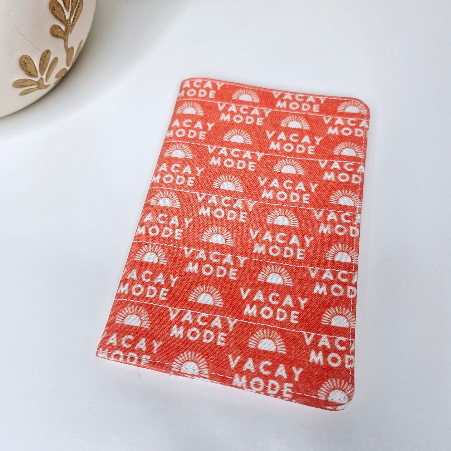 A passport cover with a 'VACAY-MODE' text and geometric patterns in orange