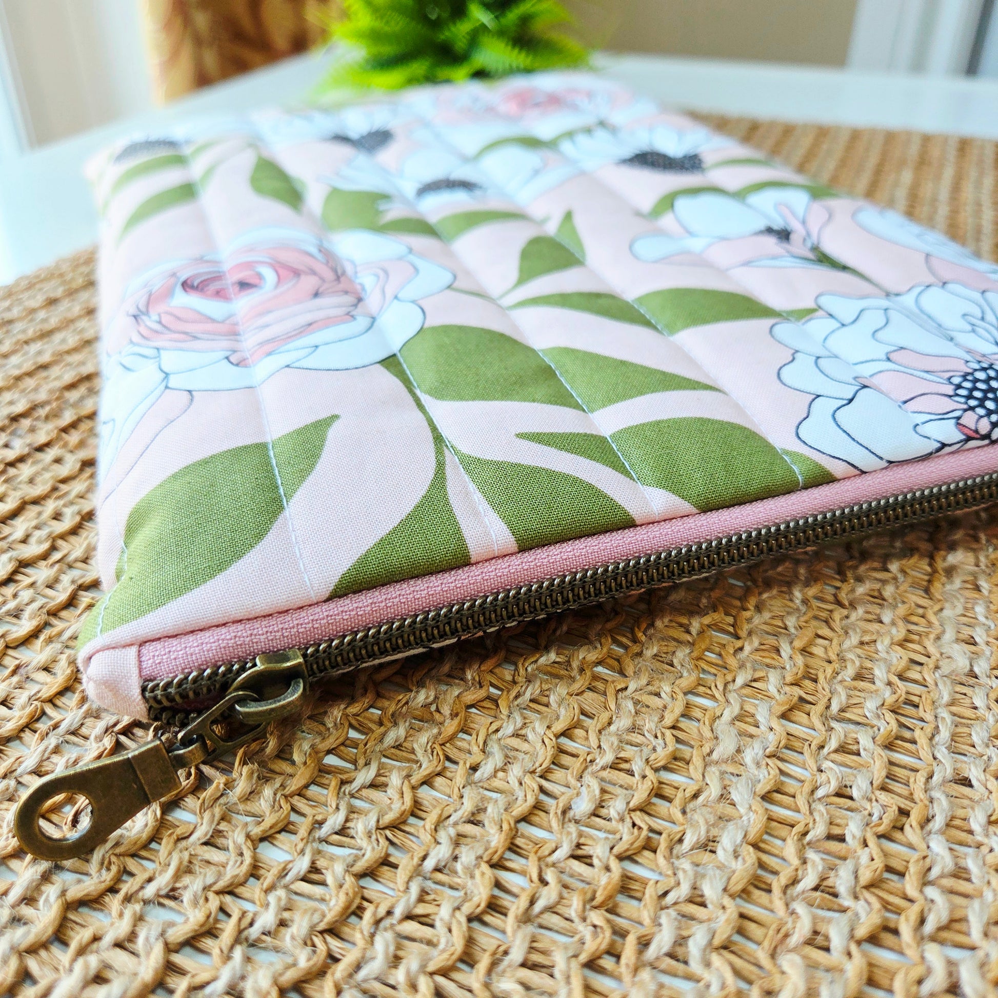 Handmade quilted iPad sleeve with pink and white floral fabric, featuring zipper closure 
