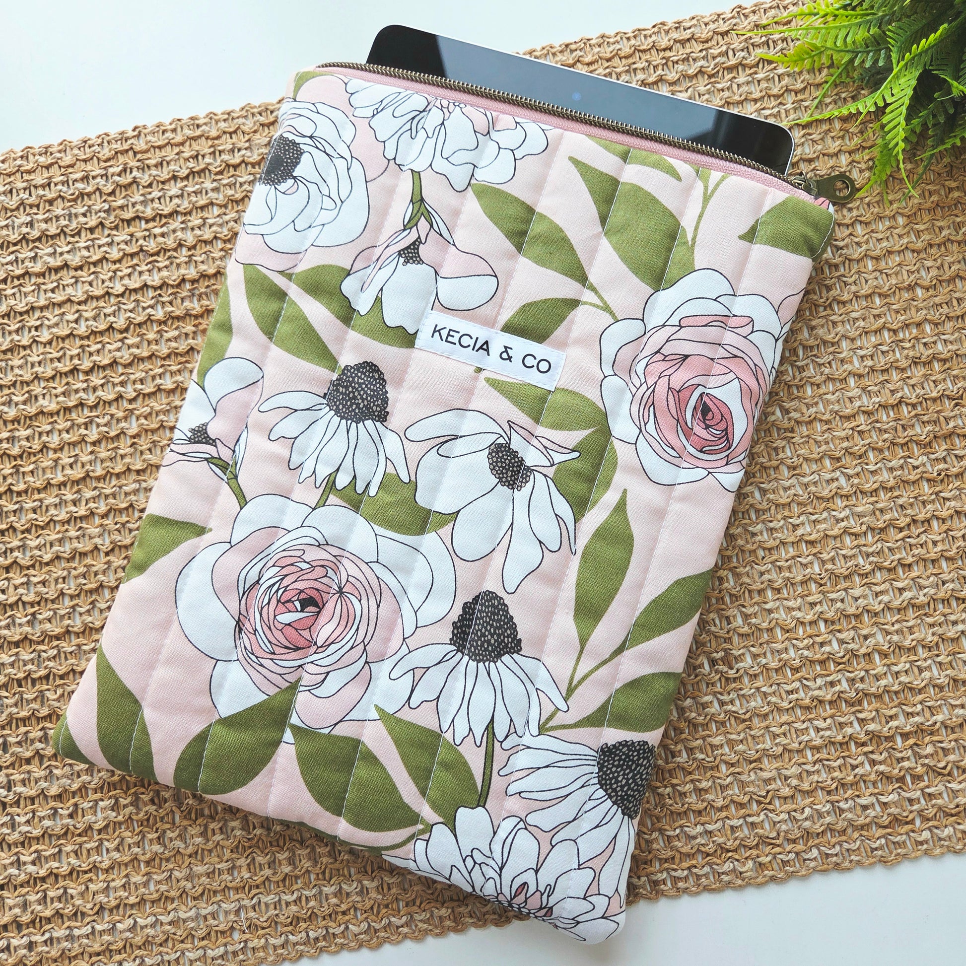 Handmade quilted iPad sleeve with pink and white floral fabric, featuring zipper closure