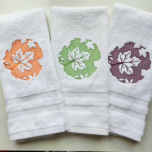 Set of 3 maple leaf embroidered cotton hand towels in orange, green, and burgundy"