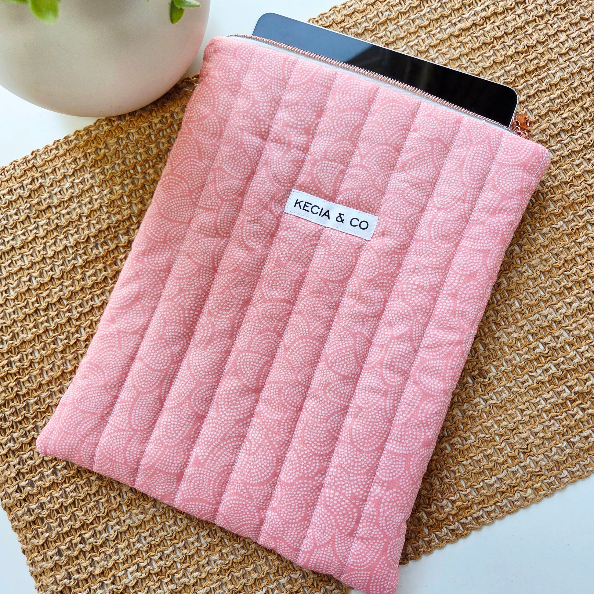 Zipper opening showing iPad inside blush pink quilted sleeve