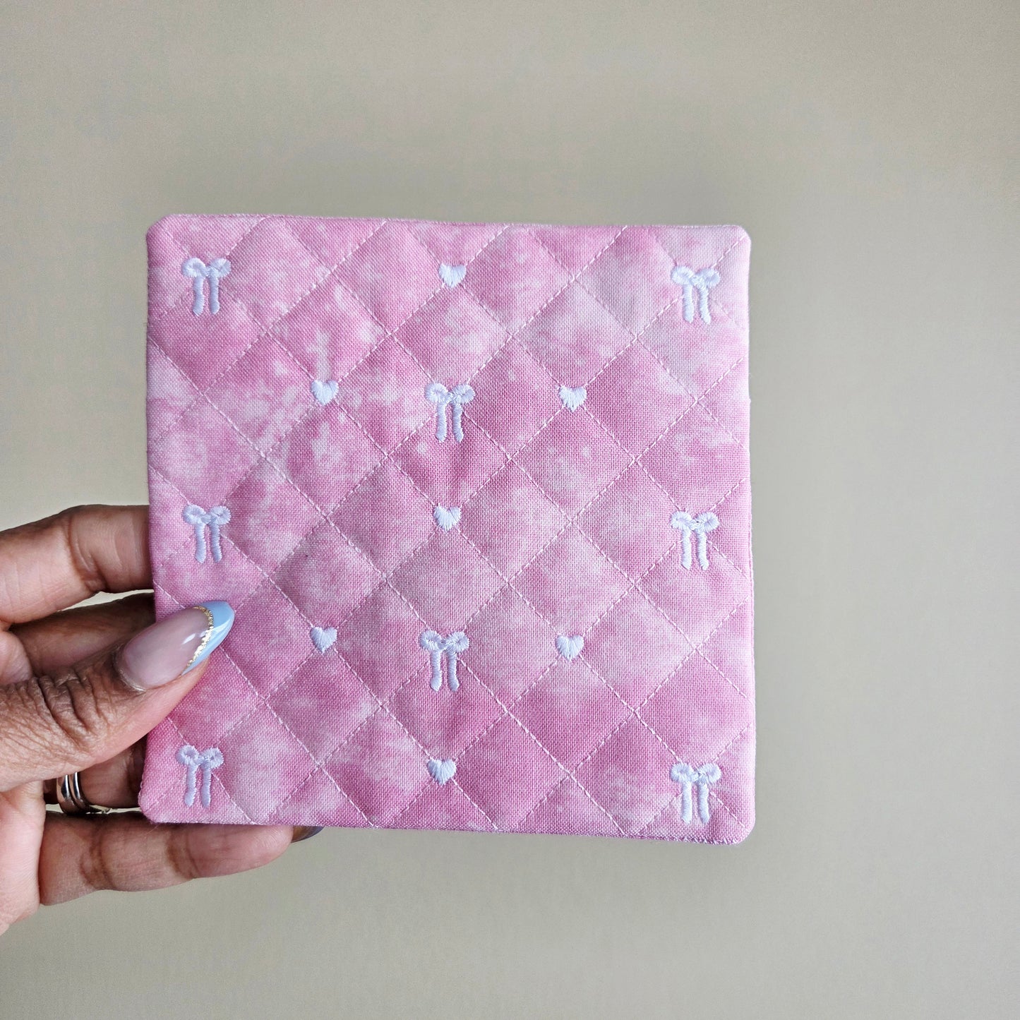 Soft pink quilted fabric coaster with delicate bow embroidery, handmade Valentine decor