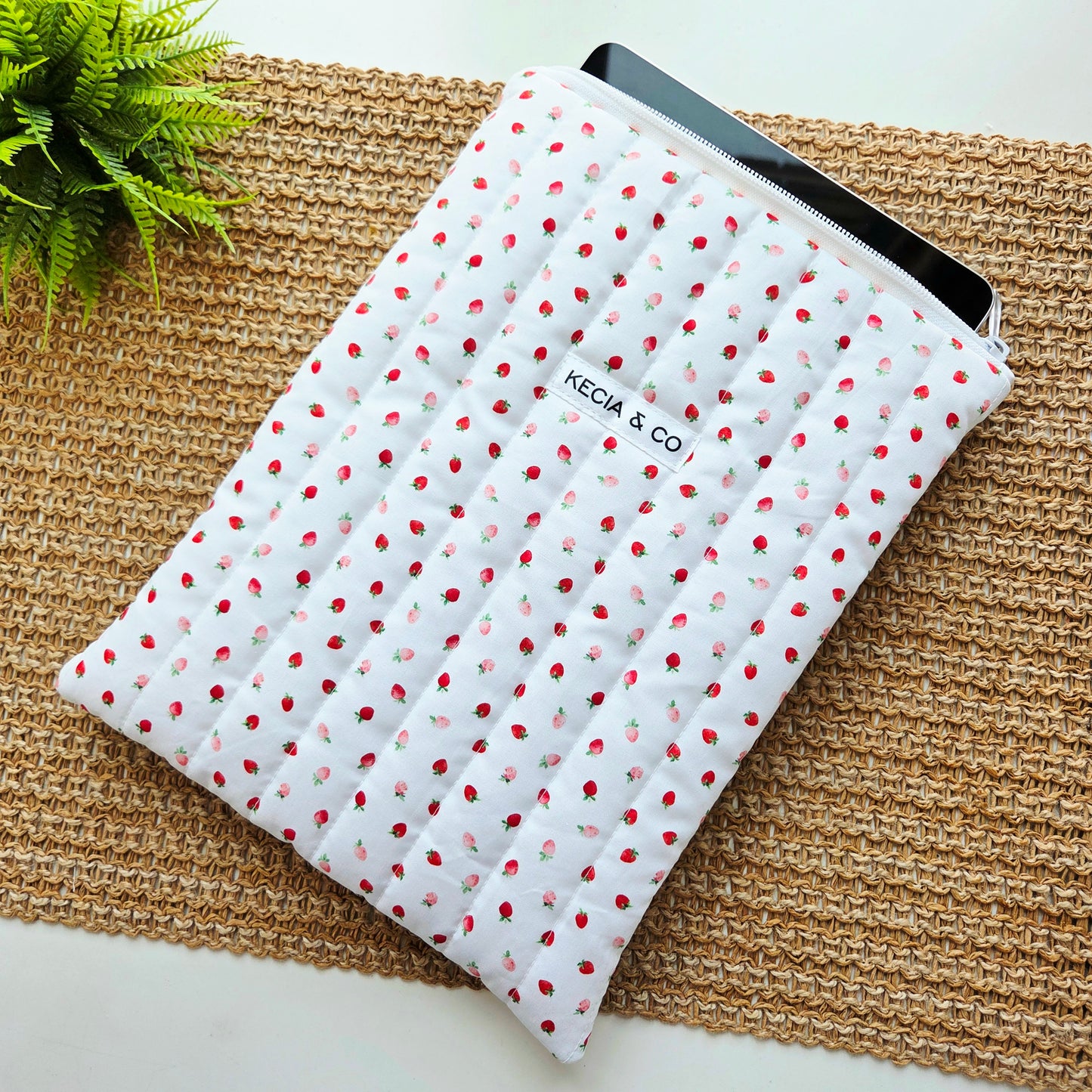 Quilted iPad sleeve with red and pink strawberry print on white fabric, handmade by Kecia & Co.