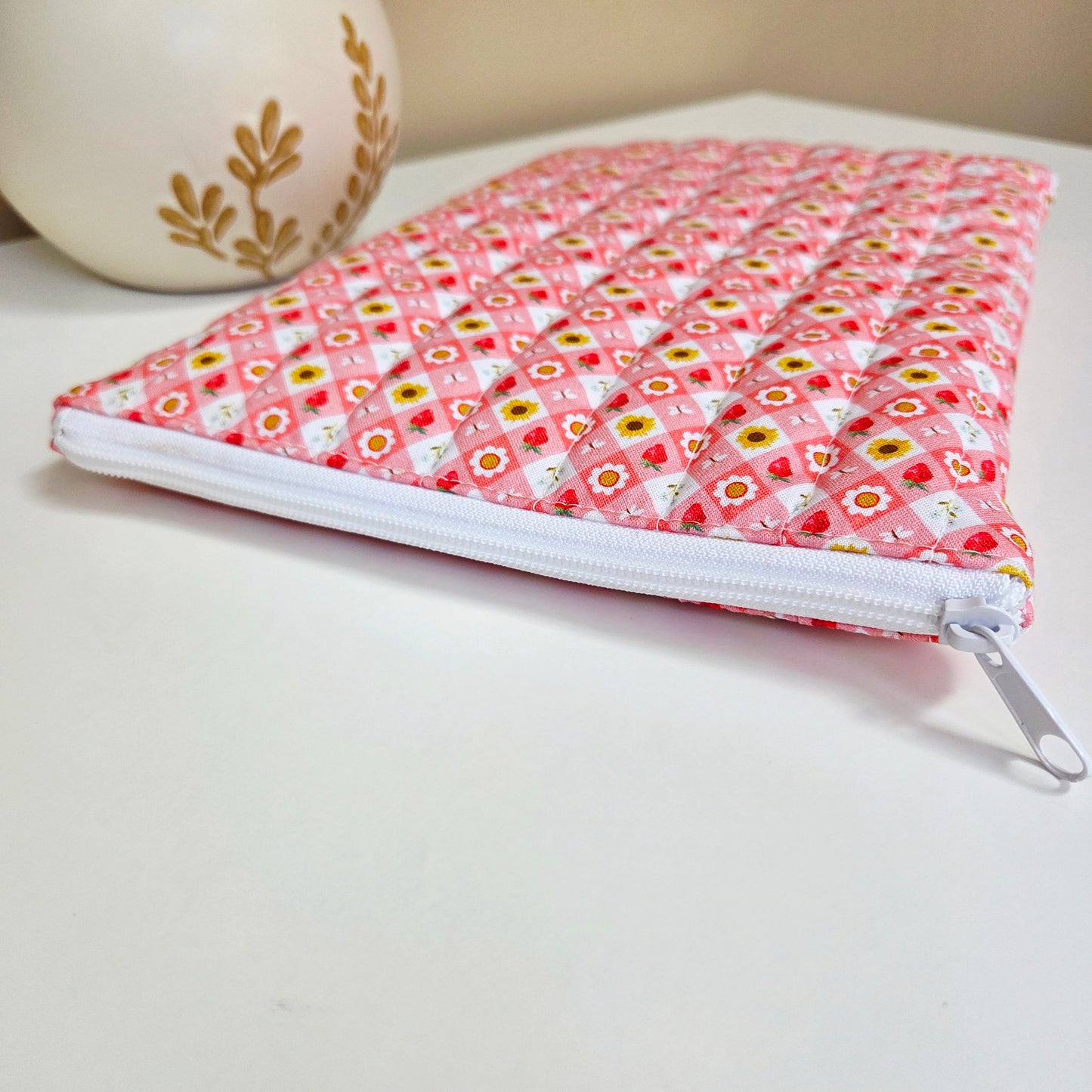 Close-up of white zipper on quilted strawberry picnic sleeve