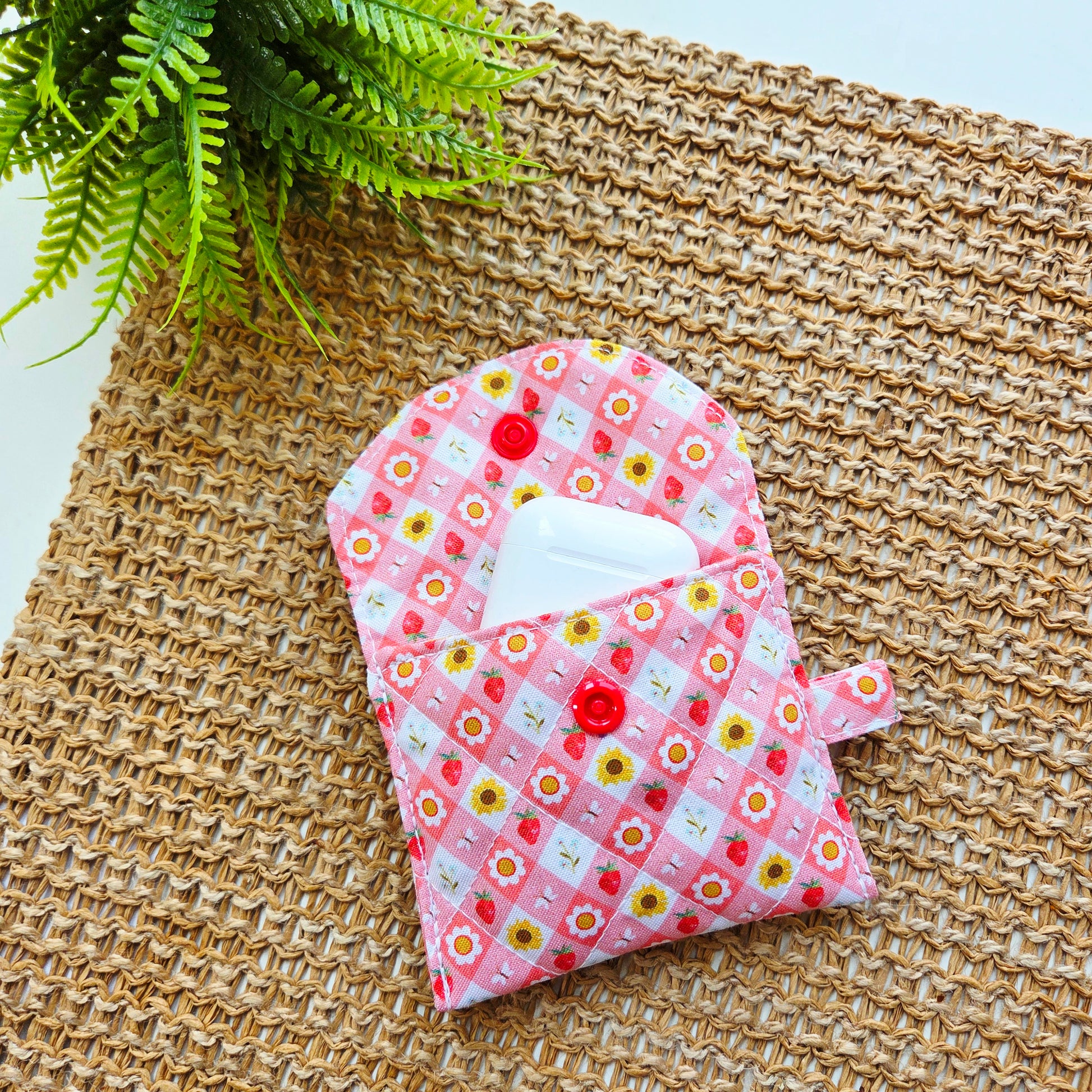 Small quilted AirPods case made with Strawberry Picnic print fabric and snap closure, perfect for clipping onto a wristlet.
