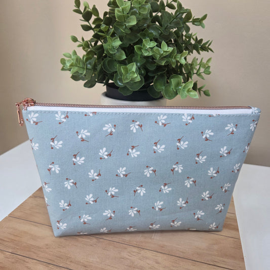 Front view of Wild Meadow zipper pouch in soft blue with tiny white floral print