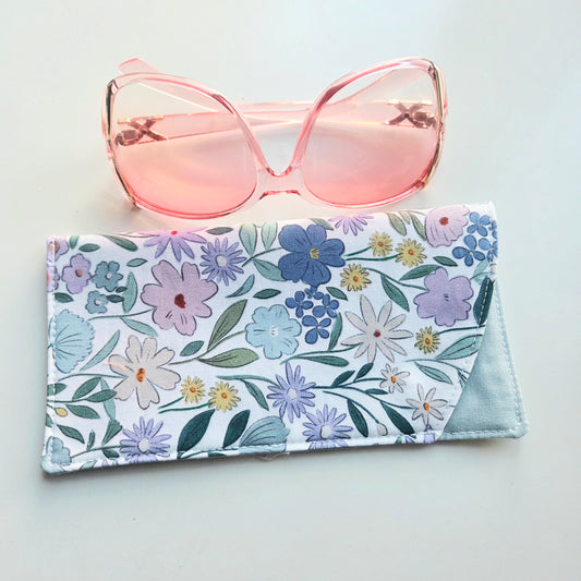 Floral sunglasses case with pink sunglasses on a light gray background